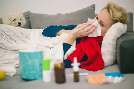 woman suffering from cold and flu lying in front of medicines kept on the table